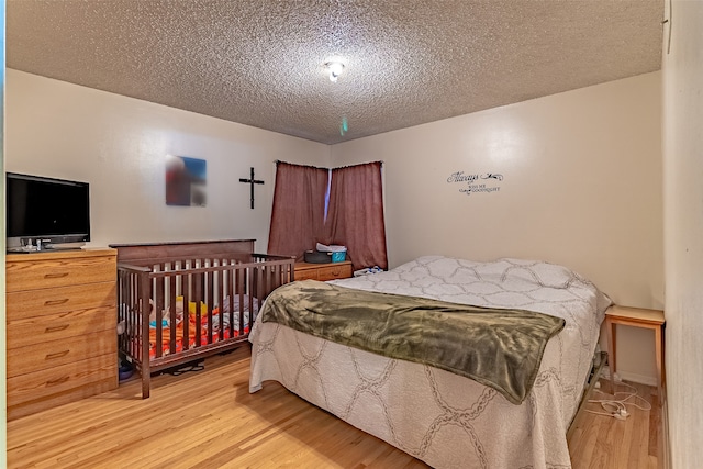 bedroom featuring light hardwood / wood-style flooring and a textured ceiling