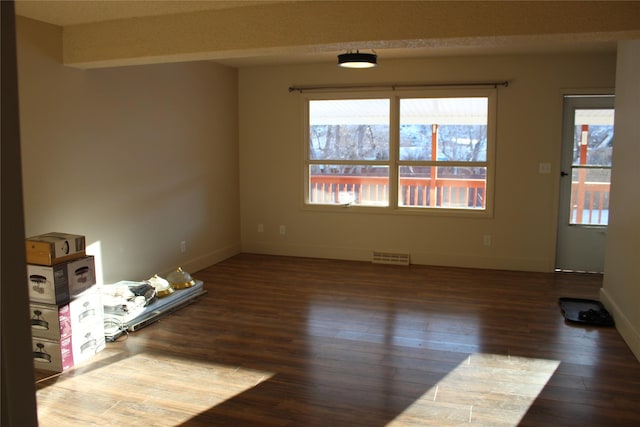 spare room with plenty of natural light and dark hardwood / wood-style floors