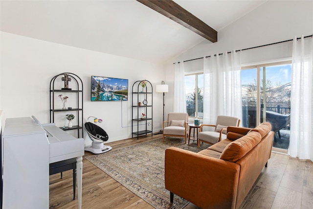 living area with lofted ceiling with beams and wood finished floors