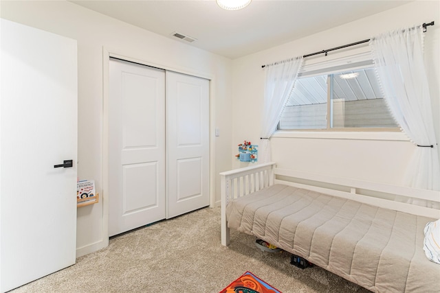 carpeted bedroom featuring a closet, visible vents, and baseboards