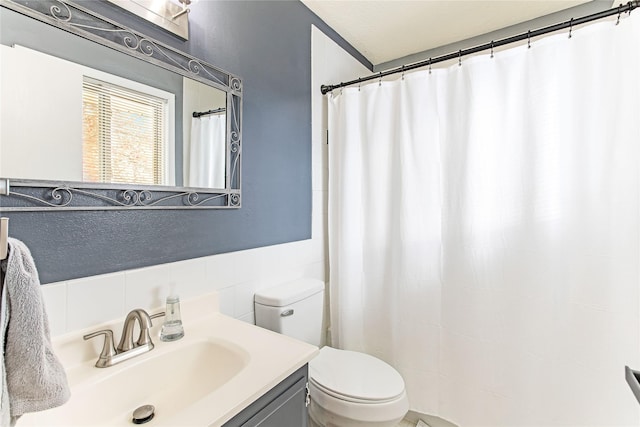 full bathroom with a textured wall, curtained shower, vanity, and toilet