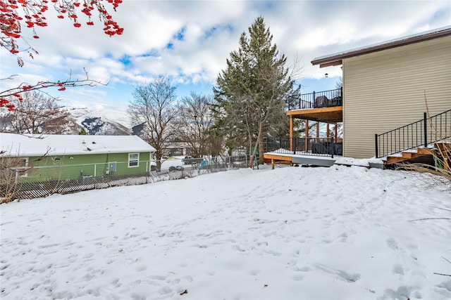 yard covered in snow with fence and a wooden deck