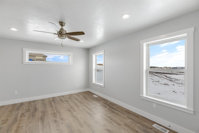 empty room with a textured ceiling, ceiling fan, and light wood-type flooring