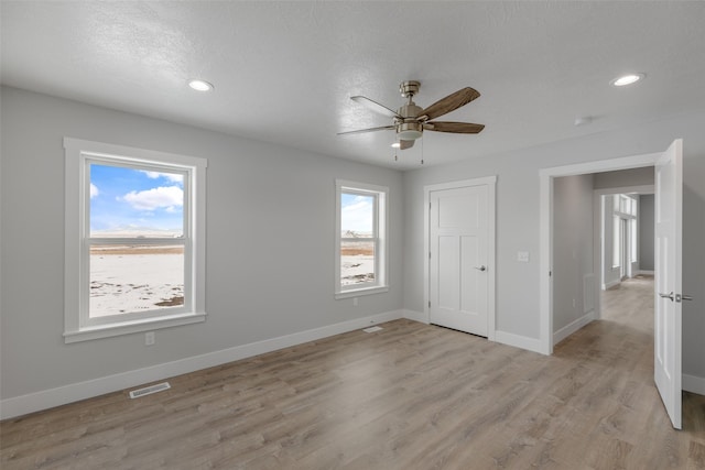 unfurnished bedroom with a textured ceiling, light hardwood / wood-style floors, and ceiling fan