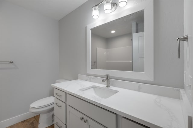 bathroom with toilet, hardwood / wood-style floors, vanity, and walk in shower