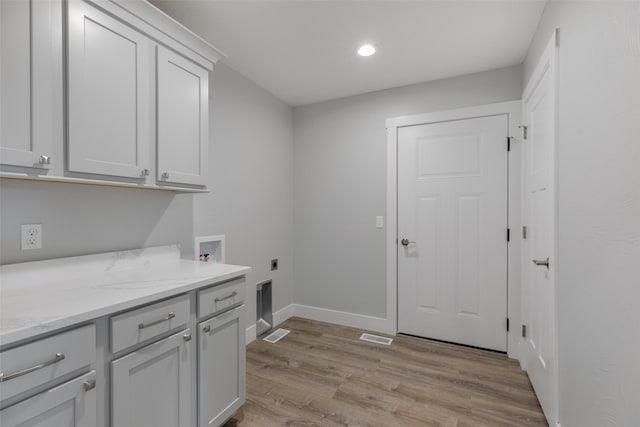 laundry room featuring cabinets, electric dryer hookup, hookup for a washing machine, and light hardwood / wood-style flooring