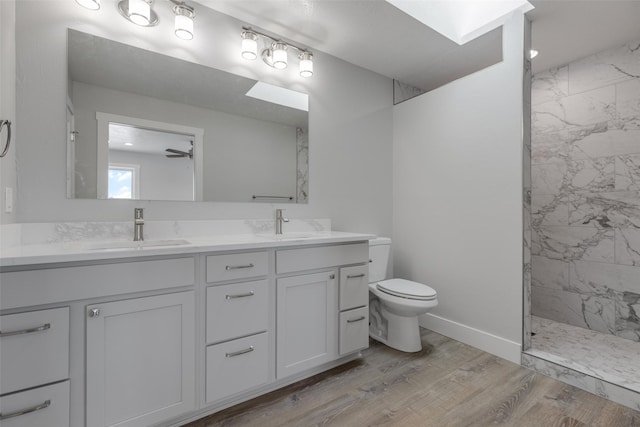 bathroom with tiled shower, toilet, a skylight, vanity, and hardwood / wood-style flooring