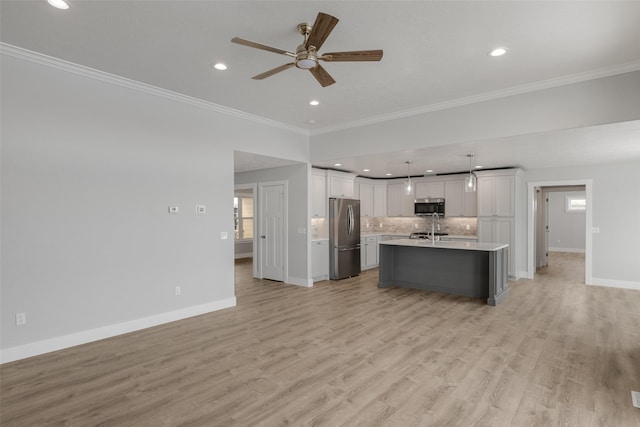 kitchen featuring white cabinetry, hanging light fixtures, stainless steel appliances, a center island with sink, and light wood-type flooring