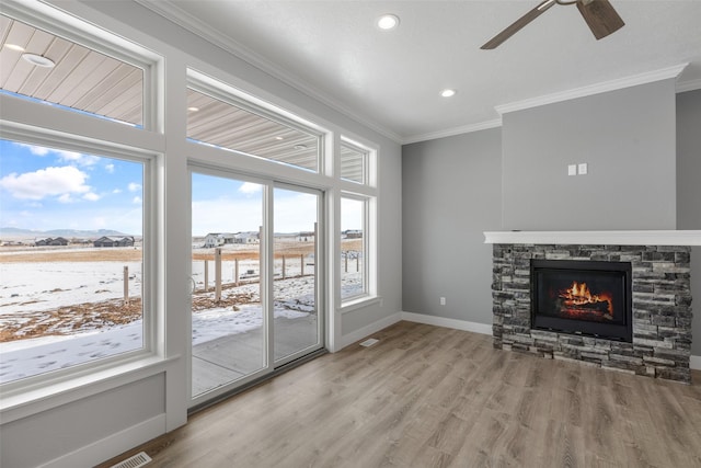 unfurnished living room featuring crown molding, ceiling fan, a fireplace, and light hardwood / wood-style floors