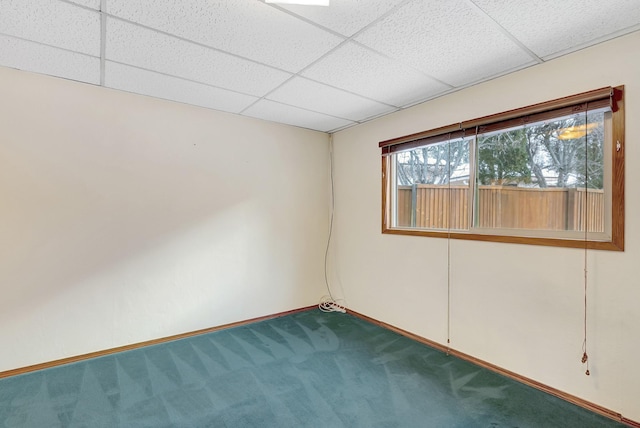 carpeted empty room featuring a paneled ceiling