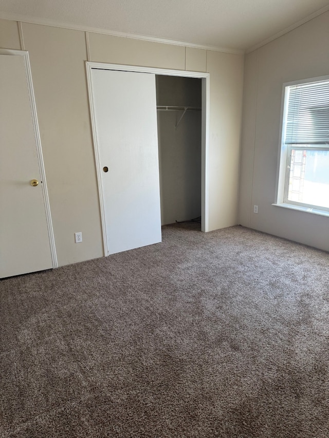 unfurnished bedroom with crown molding, a closet, and carpet
