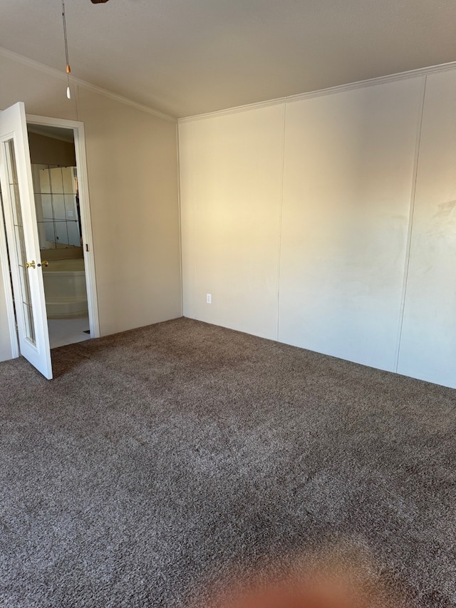 empty room featuring vaulted ceiling, crown molding, and carpet floors