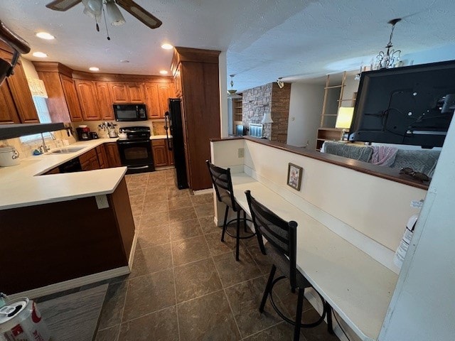 kitchen featuring decorative light fixtures, black appliances, a kitchen breakfast bar, ceiling fan, and kitchen peninsula