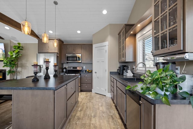 kitchen featuring sink, a center island, appliances with stainless steel finishes, pendant lighting, and light hardwood / wood-style floors