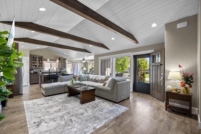 living room featuring ceiling fan, a wealth of natural light, hardwood / wood-style floors, and vaulted ceiling with beams