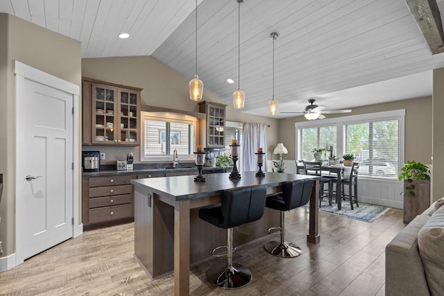 kitchen with lofted ceiling, sink, wood ceiling, a kitchen island, and decorative light fixtures