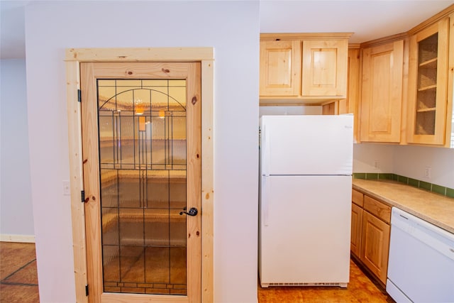 kitchen featuring white appliances, glass insert cabinets, light countertops, and light brown cabinetry