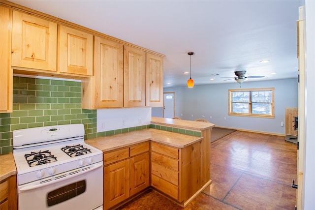 kitchen with white range with gas cooktop, a peninsula, ceiling fan, light countertops, and backsplash