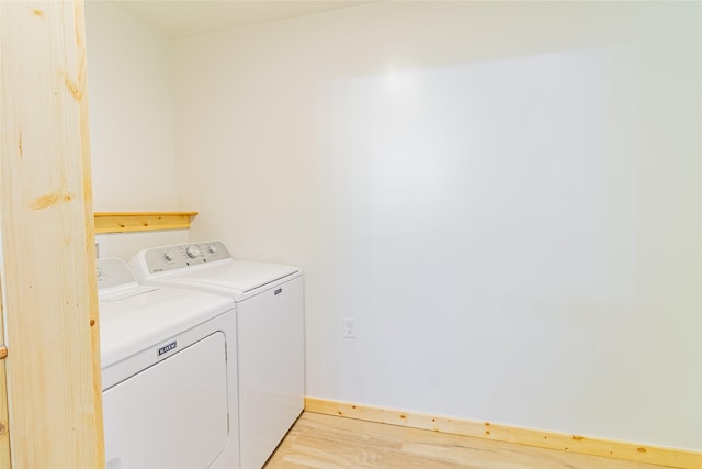 washroom with washer and dryer, light wood-type flooring, and laundry area