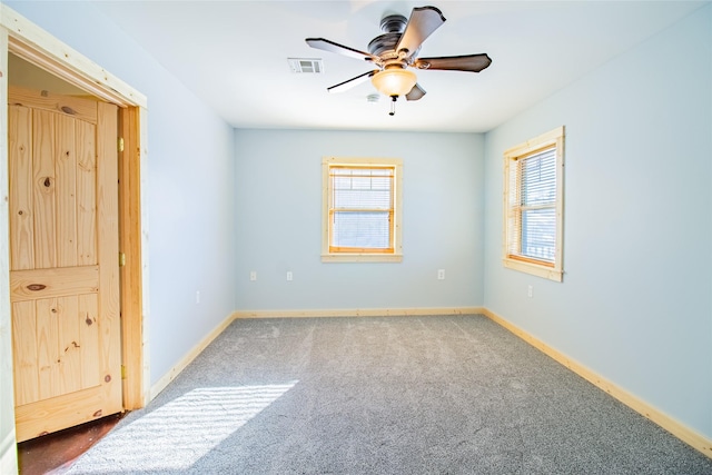 spare room with a ceiling fan, carpet flooring, baseboards, and visible vents