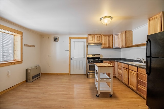 kitchen with dark countertops, gas range, freestanding refrigerator, heating unit, and a sink