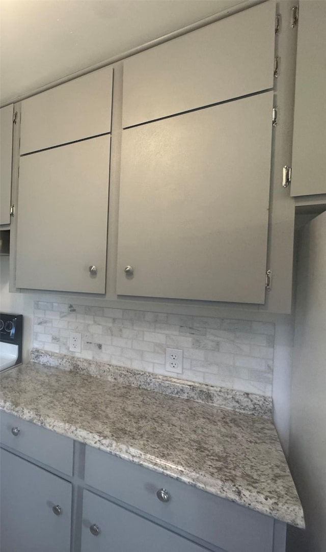 kitchen featuring tasteful backsplash, range, and gray cabinetry