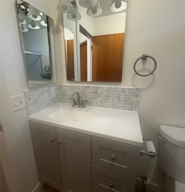 bathroom with vanity, toilet, and decorative backsplash