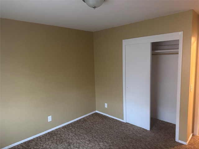 unfurnished bedroom with dark carpet and a closet