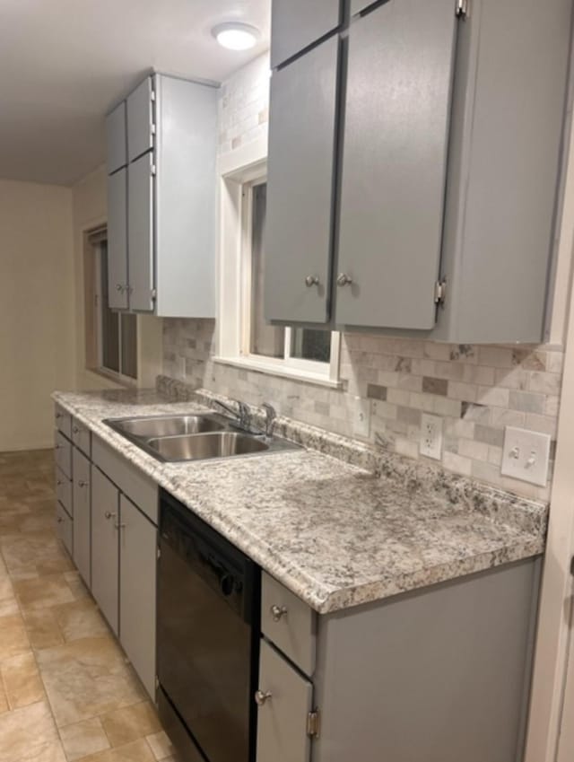 kitchen featuring tasteful backsplash, black dishwasher, sink, and gray cabinetry