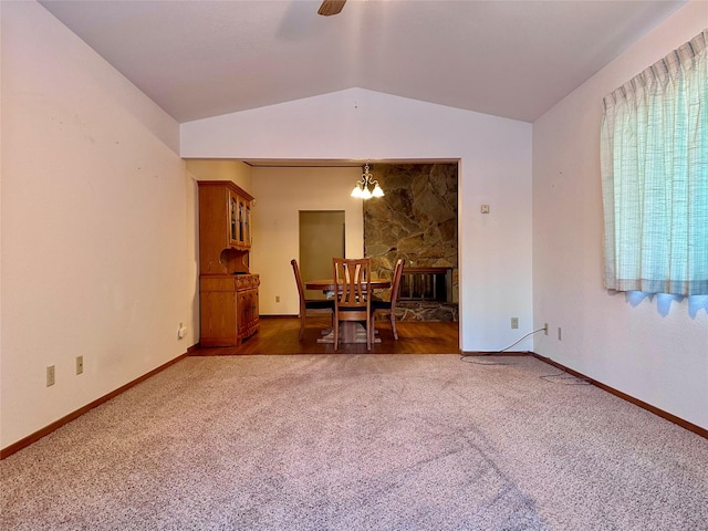 unfurnished dining area featuring lofted ceiling, ceiling fan with notable chandelier, and dark colored carpet