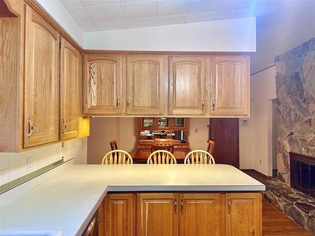 kitchen featuring a stone fireplace, lofted ceiling, dark hardwood / wood-style flooring, and kitchen peninsula