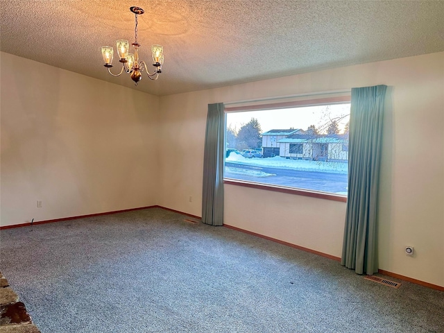 carpeted empty room with a chandelier and a textured ceiling