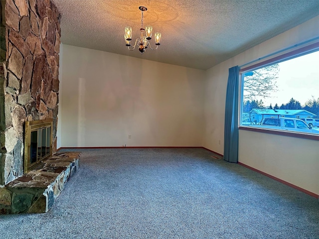 unfurnished living room featuring an inviting chandelier, carpet flooring, a stone fireplace, and a textured ceiling