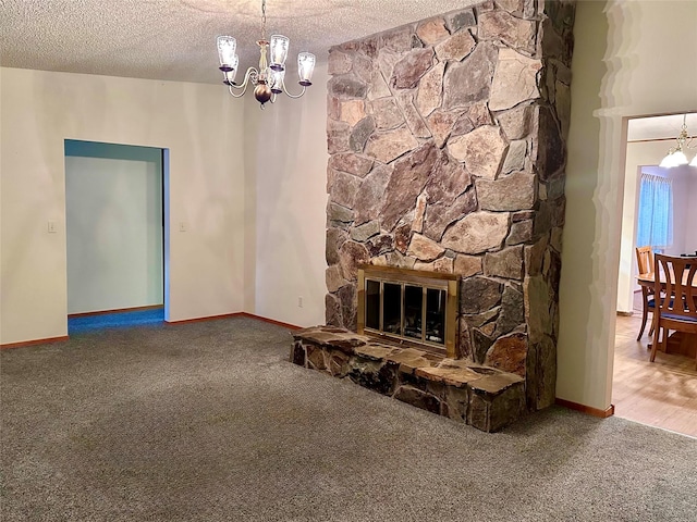 unfurnished living room featuring a textured ceiling, a fireplace, a chandelier, and carpet flooring