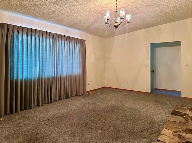 empty room featuring an inviting chandelier, a textured ceiling, and carpet