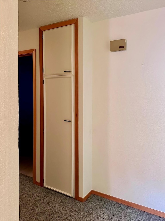 hallway with carpet floors and a textured ceiling