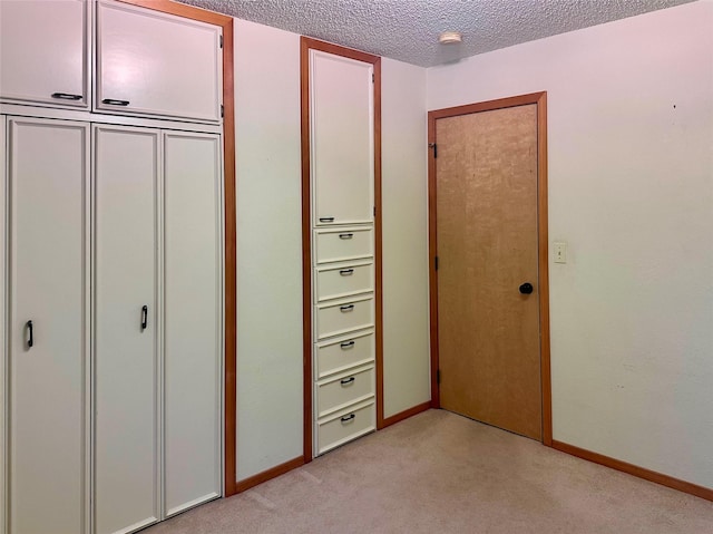 unfurnished bedroom featuring light colored carpet, a textured ceiling, and a closet