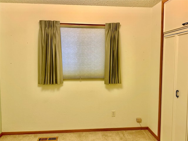 unfurnished bedroom featuring light carpet, a closet, and a textured ceiling