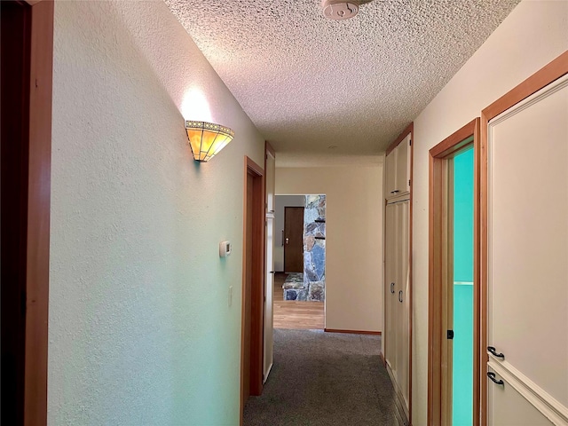 corridor with carpet and a textured ceiling