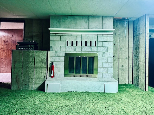 unfurnished living room with a tile fireplace and wood walls