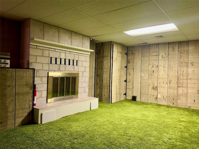 basement with a paneled ceiling, a fireplace, and wood walls