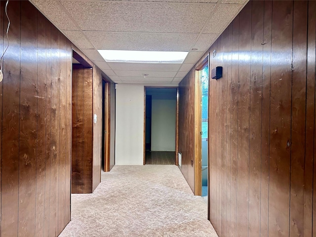 corridor featuring light carpet and wood walls