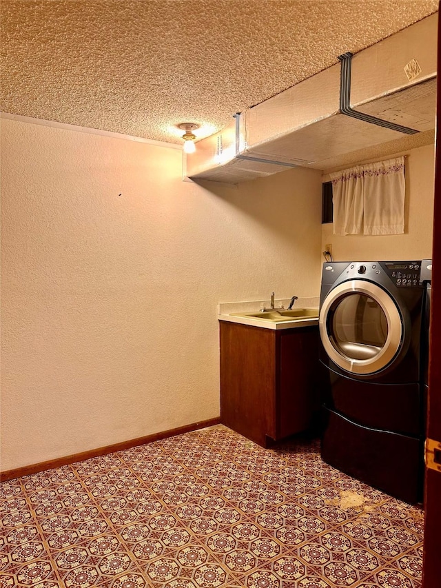 clothes washing area with sink, washer / dryer, and a textured ceiling