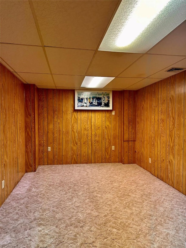 basement with a drop ceiling and wood walls