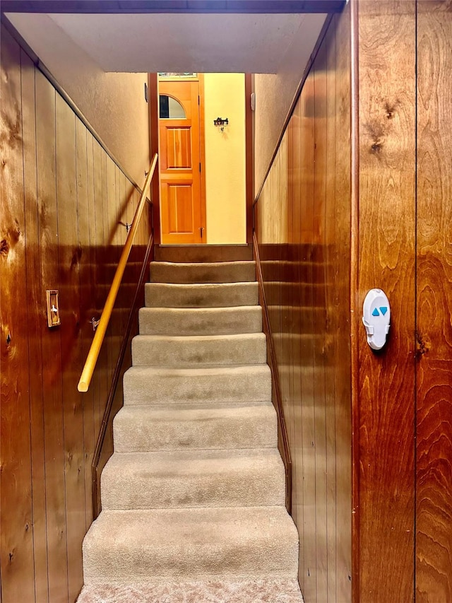 staircase featuring wood walls