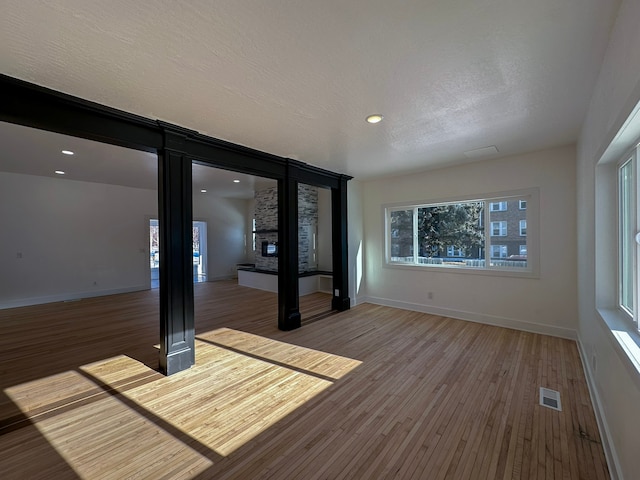 interior space with hardwood / wood-style flooring, a stone fireplace, and a textured ceiling