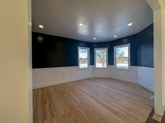 empty room featuring a textured ceiling and light hardwood / wood-style flooring