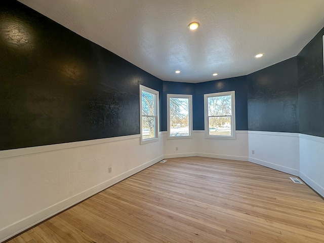 empty room with a textured ceiling and light wood-type flooring