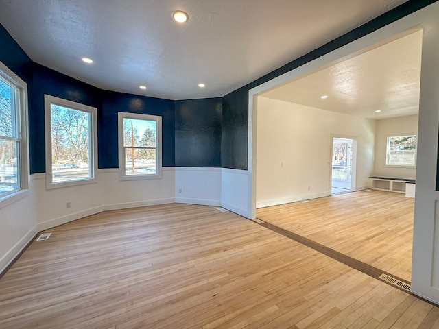 unfurnished room with light hardwood / wood-style flooring and a textured ceiling