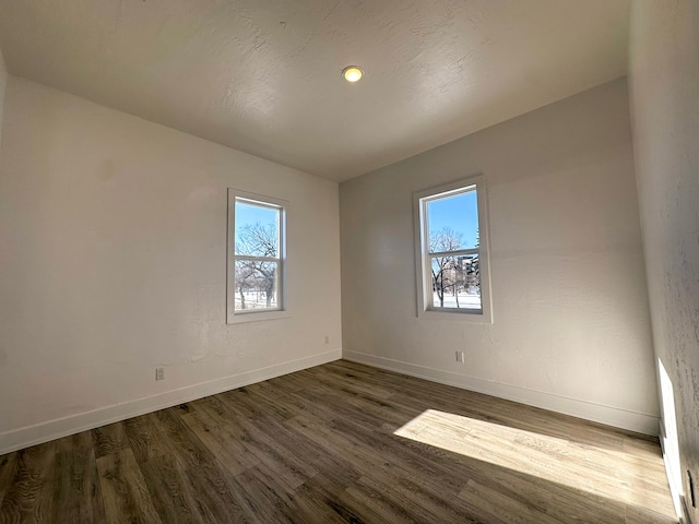 empty room with dark hardwood / wood-style flooring and a wealth of natural light